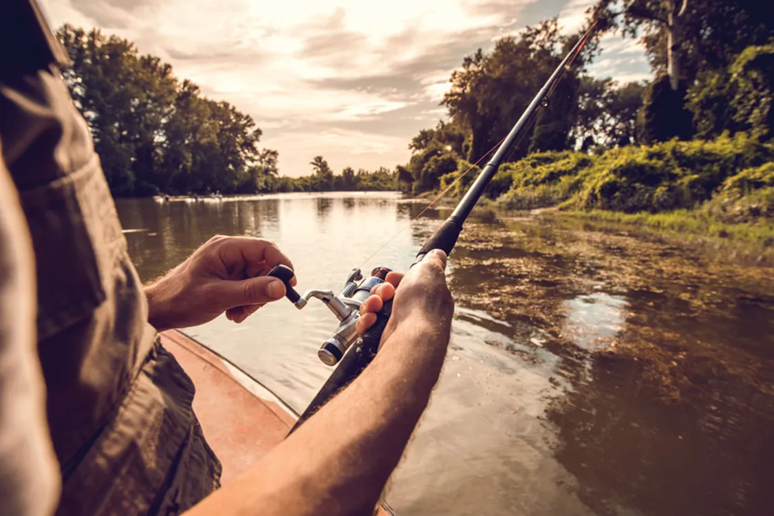 Person reels in fishing line while holding reel in right hand.