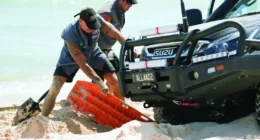 Two people using a recovery board for a stuck vehicle