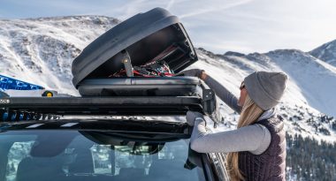 Woman loading gear into car roof cargo box.