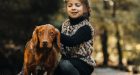 Young girl hugs brown dog on a path in the forest