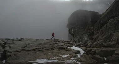 Person hikes over rocks at Pulpit Rock in Norway.