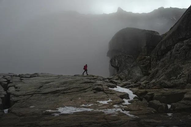 Person hikes over rocks at Pulpit Rock in Norway.